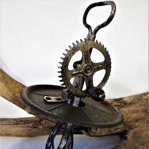 May include: Vintage hand-crank egg beater with a metal base, a gear, and a handle. The beater is made of metal and has a blue and silver finish.