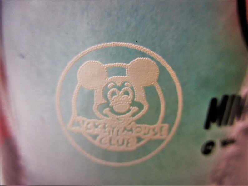 May include: A white Mickey Mouse head logo with the text "Disney Movie Club" on a light blue background.