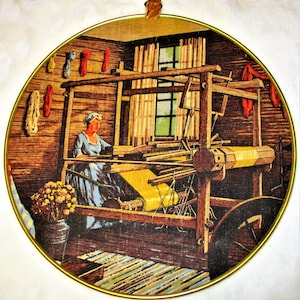 May include: A vintage illustration of a woman weaving on a loom in a rustic wooden room. The loom is made of wood and has a yellow fabric being woven. The woman is wearing a blue dress and a white cap. The room has a wooden floor and a window with white curtains.