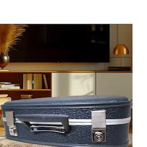 May include: A dark blue hard-shell case with a white stripe and silver clasps. The case has a silver handle and a textured surface.