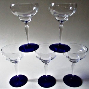 May include: Set of six clear glass margarita glasses with blue bases. The glasses are stacked in a pyramid shape.