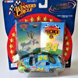 May include: A blue and yellow NASCAR die-cast car with the number 24 on the side. The car is a Monte Carlo 400 Rematch and features a Bugs Bunny design. The car is packaged with two collector cards.