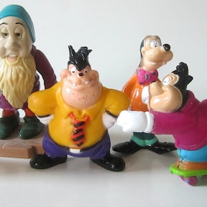 May include: A set of seven plastic Disney character figurines. The characters include Mickey Mouse, Minnie Mouse, Goofy, and a dwarf. The figurines are all in various poses and are brightly colored.