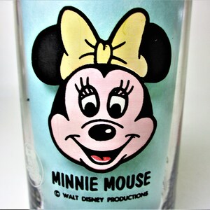 May include: A blue glass featuring a cartoon image of Minnie Mouse wearing a yellow bow. The text "Minnie Mouse" and "Walt Disney Productions" is printed below the image.