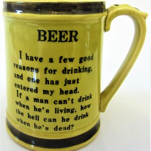 May include: A yellow ceramic beer mug with a black handle and a black rim. The mug has a black inscription that reads "BEER I have a few good reasons for drinking, and one has just entered my head. If a man can't drink when he's living, how the hell can he drink when he's dead?"