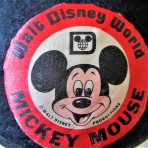 May include: Red and white circular patch with the text "Walt Disney World Mickey Mouse" and a cartoon image of Mickey Mouse. The patch also includes the Walt Disney Productions copyright and the Disney logo with a globe.