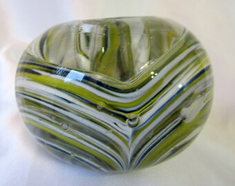 May include: A clear glass vase with a swirl pattern of white, green, and black stripes. The vase has a rounded shape and is perfect for displaying flowers.