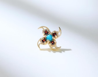 May include: A gold-toned earring with a turquoise center stone surrounded by four smaller red stones. The earring has a delicate, intricate design.