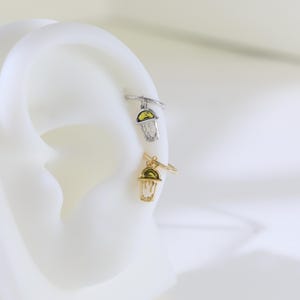 Peut inclure: Deux boucles d'oreilles dor&eacute;es et argent&eacute;es avec des breloques pendantes. Les breloques sont en forme de cornets de glace avec un motif jaune et vert.