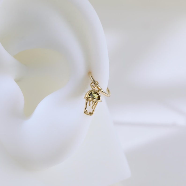 Peut inclure: Boucle d'oreille en or avec un pendentif en forme de gobelet &agrave; caf&eacute; glac&eacute; vert.