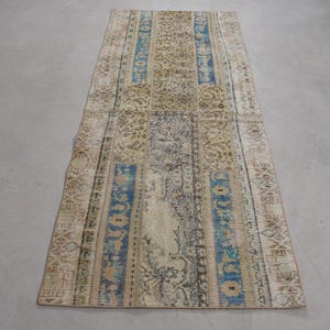 Puede incluir: Una alfombra de pasillo vintage con fondo crema y rayas con patrones azules y beige. La alfombra tiene un aspecto desgastado y está hecha de tejido tejido.