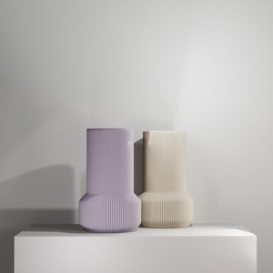Op de afbeelding: Twee decoratieve vazen, een in lichtpaarse kleur en de andere in lichtbeige kleur. Beide vazen hebben een geplisseerd ontwerp en een brede basis.