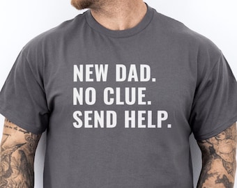 May include: A dark gray t-shirt with the text "NEW DAD. NO CLUE. SEND HELP." printed in white.