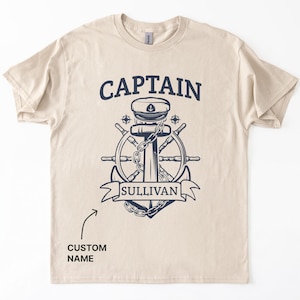 Sand Colored cotton t-shirt with bold navy graphic featuring a captain’s hat, anchor, ship wheel, and personalized name banner reading “SULLIVAN,”