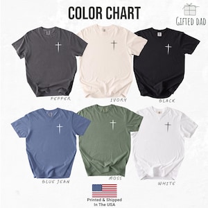 May include: A color chart displays six short-sleeved t-shirts in various colors: pepper, ivory, black, blue jean, moss, and white. Each shirt features a white cross graphic on the front. The text "COLOR CHART" is at the top.