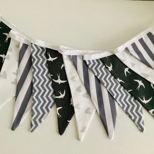 May include: A black and white bunting with a variety of patterns, including stripes, zigzags, and birds. The bunting is made of fabric and has a white string for hanging.