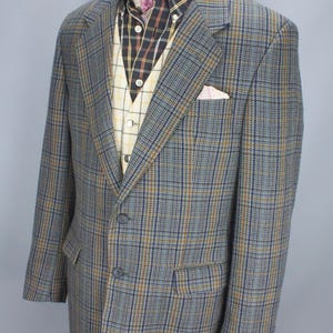 May include: A gray, blue, and brown plaid blazer with a matching vest and patterned shirt. The blazer has two front pockets and a pocket square. The outfit is displayed on a mannequin.