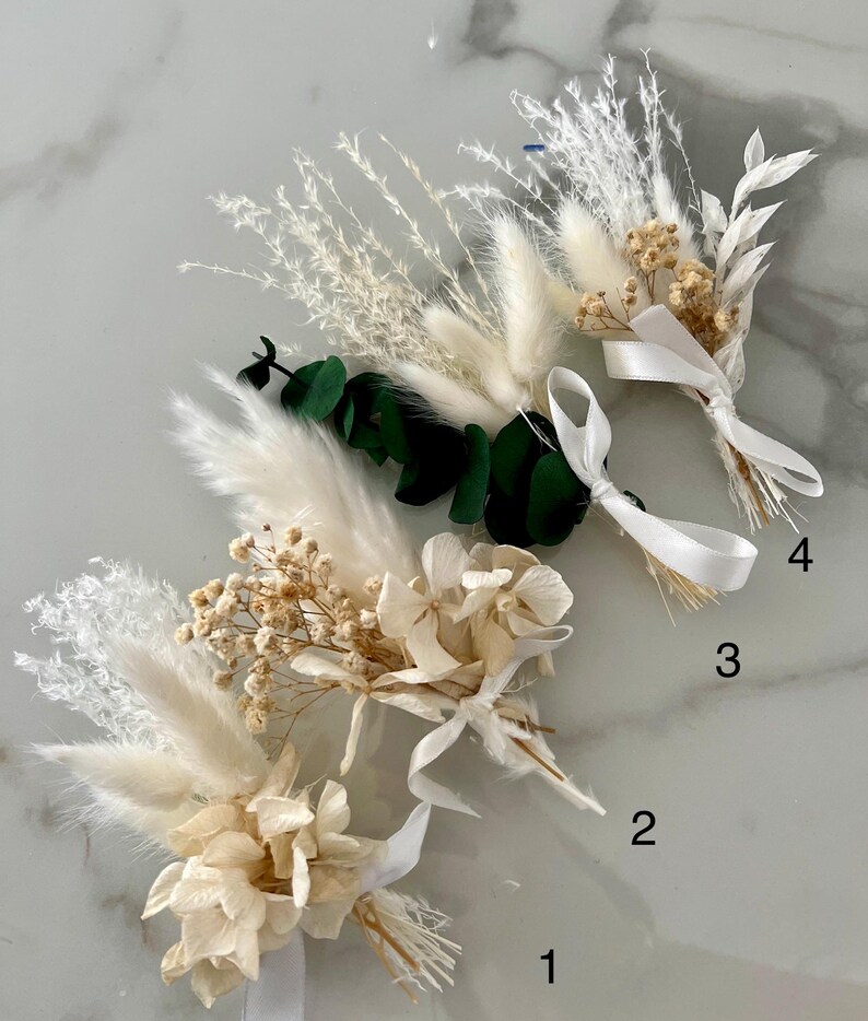May include: Four bouquets of dried flowers with white ribbon. The bouquets are arranged in a row from left to right, numbered 1 through 4. Each bouquet includes white pampas grass, white hydrangeas, and small white flowers.
