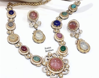 May include: A gold necklace and earring set with a variety of coloured gemstones, including pink, blue, green, and clear stones. The necklace has a large, central pink stone pendant. The set is labelled "Fusion Necklace".