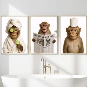 May include: Three framed prints featuring monkeys in a bathroom setting. One monkey wears a towel on its head and cucumber slices on its eyes. Another reads a newspaper titled "Monkey News Daily." The third has a toilet paper roll on its head.