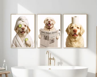 May include: Three framed prints showing golden retrievers in amusing bathroom scenarios. One dog wears a towel and cucumber slices, another reads a newspaper, and the third has a toilet roll on its head. The prints are displayed above a white bathtub.