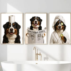 Op de afbeelding: Drie ingelijste prints met Berner Sennenhonden in humoristische badkamerscènes. Eén hond heeft een toiletpapierrol op zijn hoofd, een andere leest "Dog News Daily" en de derde draagt een badjas en komkommerschijfjes.