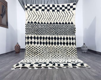May include: Black and white geometric patterned rug with fringe. The rug has a checkered pattern, diamond shapes, and a small dot pattern.
