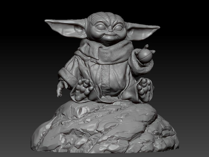 May include: A gray, 3D printed figurine of a character from the Star Wars franchise, known as "The Child" or "Baby Yoda", sitting on a rock. The character is wearing a brown robe and holding a small, round object in its hand.