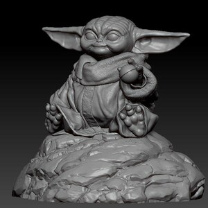 May include: A gray, 3D printed figurine of a character from the Star Wars franchise, sitting on a rocky base. The character is wearing a robe and holding a small, round object.