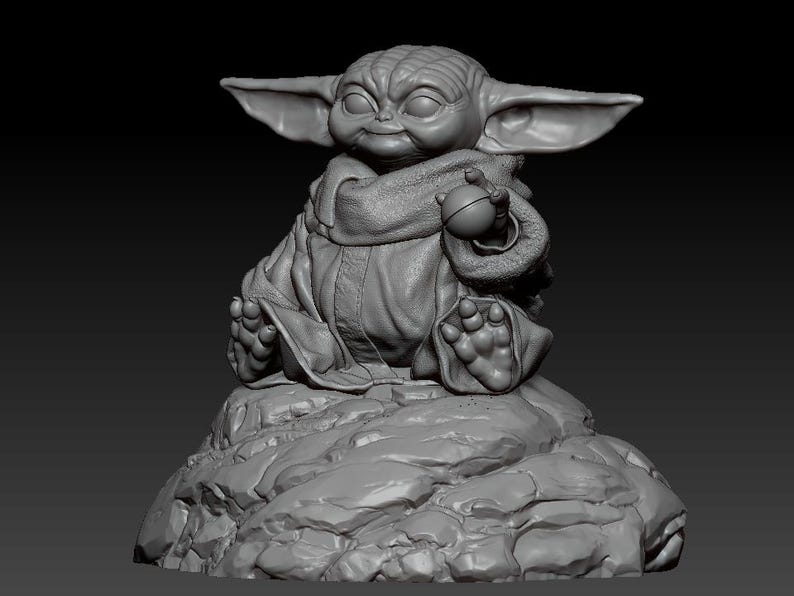 May include: A gray, 3D printed figurine of a character from the Star Wars franchise, sitting on a rocky base. The character is wearing a robe and holding a small, round object.