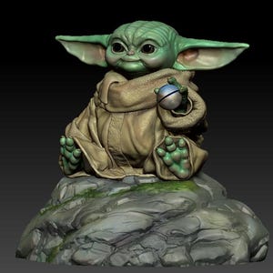 May include: A green and brown figurine of a character from the Star Wars franchise, sitting on a rock with a small sphere in its hand.