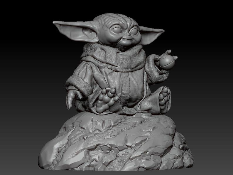 May include: A gray, 3D printed figurine of a character from the Star Wars franchise, sitting in a meditative pose on a rocky base. The character has large ears, a green skin tone, and is holding a small, round object in one hand.