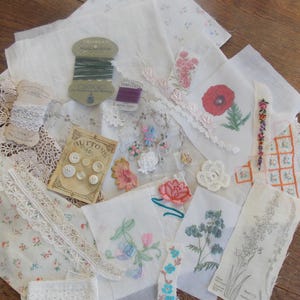 Puede incluir: Surtido de retazos de tela blanca con flores bordadas, ribetes de encaje y botones. Los retazos de tela presentan varios diseños florales, incluyendo una amapola, una rama de nomeolvides y un racimo de campanillas. Los retazos están dispuestos sobre una superficie de madera.
