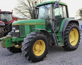 May include: A green John Deere 6800 tractor with large black tyres and yellow rims. The tractor has a cab with a windscreen and side mirrors. Another red tractor is partially visible in the background.