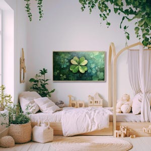 May include: A green four-leaf clover painting in a wooden frame, hanging on a white wall in a nursery with a wooden bed and green plants.