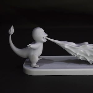 May include: A gray figurine of a cartoon character, with a flame-shaped effect emanating from its mouth. The figure is standing on a rectangular base. The background is dark.