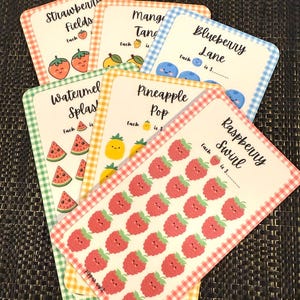 Puede incluir: Un conjunto de tarjetas coloridas con temática de frutas y borde de cuadros. Cada tarjeta presenta una ilustración de fruta diferente, incluyendo fresas, mangos, arándanos, sandía, piña y frambuesas, con el texto "Strawberry Fields", "Mango Tang", "Blueberry Lane", "Watermelon Splash", "Pineapple Pop" y "Raspberry Swirl".