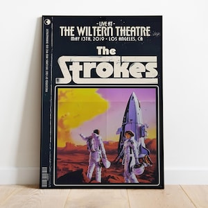 May include: A black and white poster with a retro design featuring the band The Strokes. The poster advertises a concert at The Wiltern Theatre in Los Angeles, California on May 13th, 2019. The poster features a rocket ship and two figures in space suits.