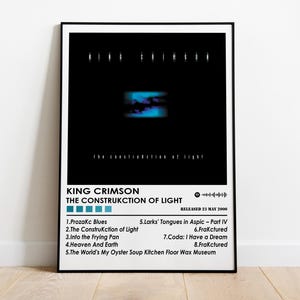 Pode incluir: Um pôster de capa de álbum em preto e branco para o álbum de King Crimson "The Construction of Light". A capa do álbum apresenta um design abstrato azul e roxo. O título do álbum e o nome do artista estão impressos em branco. O álbum foi lançado em 23 de maio de 2000.