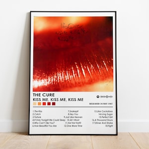 May include: A framed poster featuring the album art for The Cure's "Kiss Me, Kiss Me, Kiss Me." The artwork is a close-up of red lips. The poster includes the album title, tracklist, and release date.