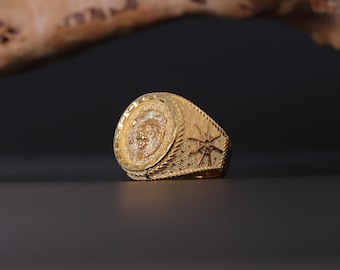 May include: A gold ring with a lion head design on the front and a starburst design on the band.