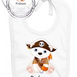 Puede incluir: Un juego de babero y chupete para bebé blancos. El babero y el chupete presentan un oso polar de dibujos animados con un sombrero de pirata. El babero y el chupete tienen la palabra "Prénom".