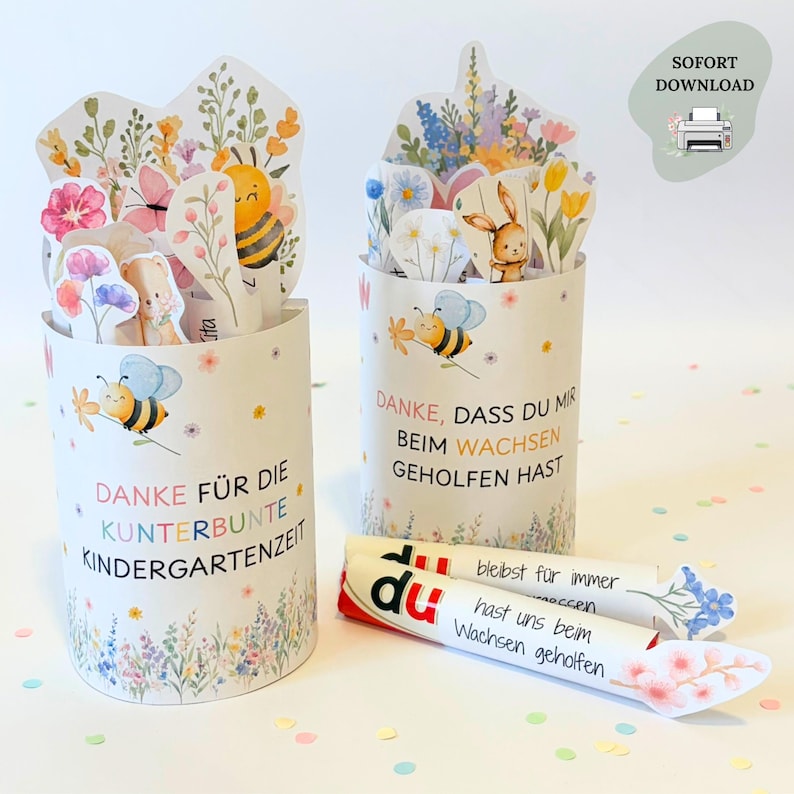 Puede incluir: Dos recipientes cil&iacute;ndricos de papel decorados con ilustraciones en acuarela de abejas, flores y conejos. El texto dice "DANKE F&Uuml;R DIE KUNTERBUNTE KINDERGARTENZEIT" y "DANKE, DASS DU MIR BEIM WACHSEN GEHOLFEN HAST". Se incluyen dos rollos de papel con texto.