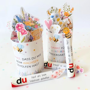 Puede incluir: Dos recipientes cil&iacute;ndricos de papel decorados con ilustraciones florales coloridas, abejas y un osito de peluche. El texto dice: DANKE, DASS DU MIR BEIM WACHSEN GEHOLFEN HAST, DANKE F&Uuml;R KUNTERBUNTE KINDERGARTEN, du hast ein riesiges Herz f&uuml;r Kinder, du bringst so viel in die Welt.
