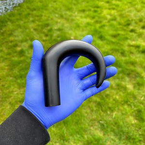 Peut inclure: Une poignée de canne noire incurvée. La poignée est faite d'un matériau lisse et dur et a une forme arrondie et ergonomique.