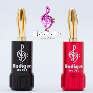 May include: Two gold-plated speaker banana plugs with black and red bodies. The plugs are labeled "Radique audio" and feature a treble clef logo.