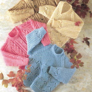 Könnte beinhalten: Vier gestrickte Pullover in verschiedenen Farben und Mustern. Ein hellrosa Pullover mit einem Zopfmuster, ein hellblauer Pullover mit einem Spitzenmuster, ein cremefarbener Pullover mit einem Spitzenmuster und ein beiger Pullover mit einem Zopfmuster.