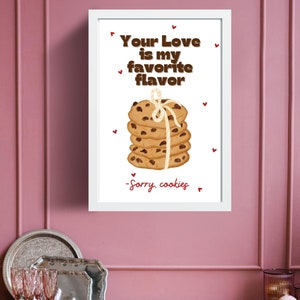 May include: A white framed print with the text "Your Love is my favorite flavor" and a stack of chocolate chip cookies tied with twine. The text "Sorry, cookies" is written below the cookies.