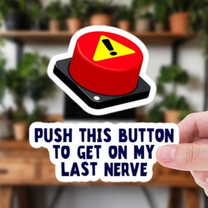 Peut inclure: Un autocollant avec un bouton rouge et un triangle jaune avec un point d'exclamation. Le texte en dessous dit : « PUSH THIS BUTTON TO GET ON MY LAST NERVE ».