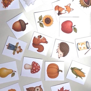 May include: A collection of square cards featuring watercolor illustrations of autumn-themed subjects including a kite, rake, ghost, leaves, chestnut, fox, acorn, sunflower, apple, scarecrow, squirrel, hedgehog, lantern, pear, mushroom, pumpkin, corn, owl, umbrella, puddle, and boot.